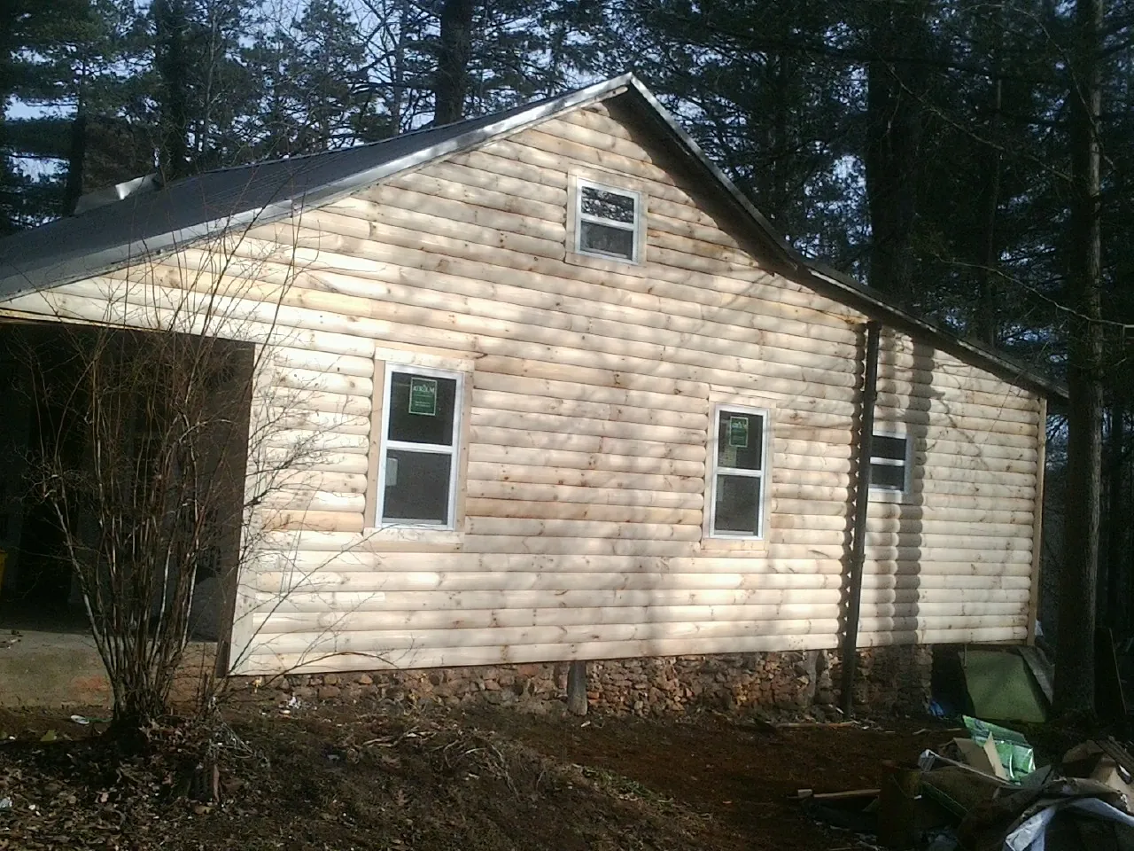 New log siding and dark metal roofing on a gable end in Atomic City