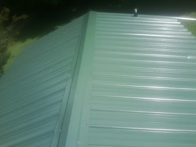 New green metal panels meeting at the ridge of a roof — Flat Roof Repair work by our crew in Atomic City