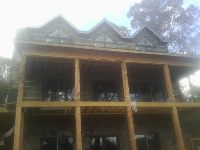 Dormers and porch framing on a large log home under construction — Roof Coating work by our crew in Atomic City
