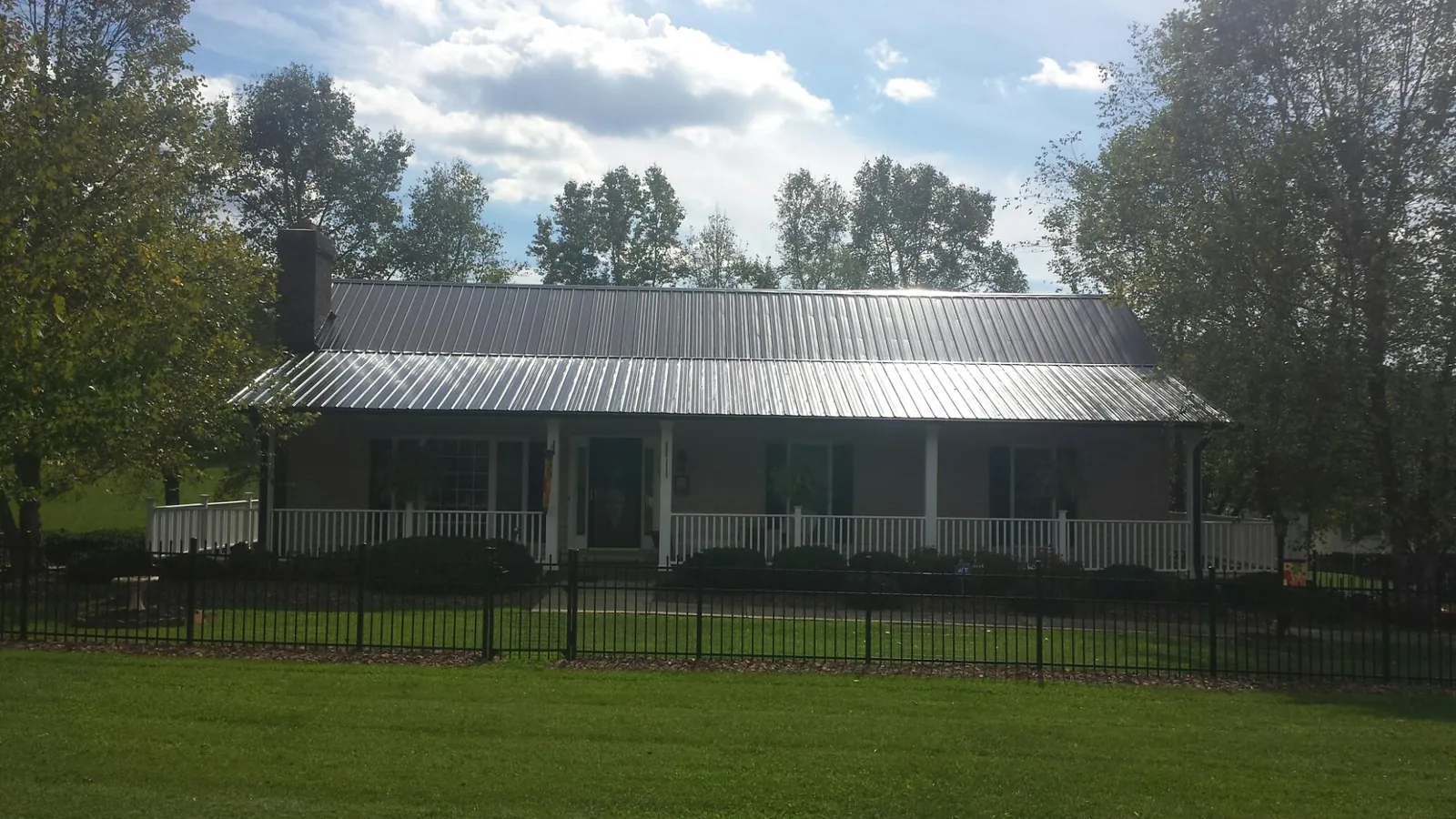 Gray metal roof on a brick ranch with a full width front porch — Gutter Guard Installation work by our crew in Atomic City