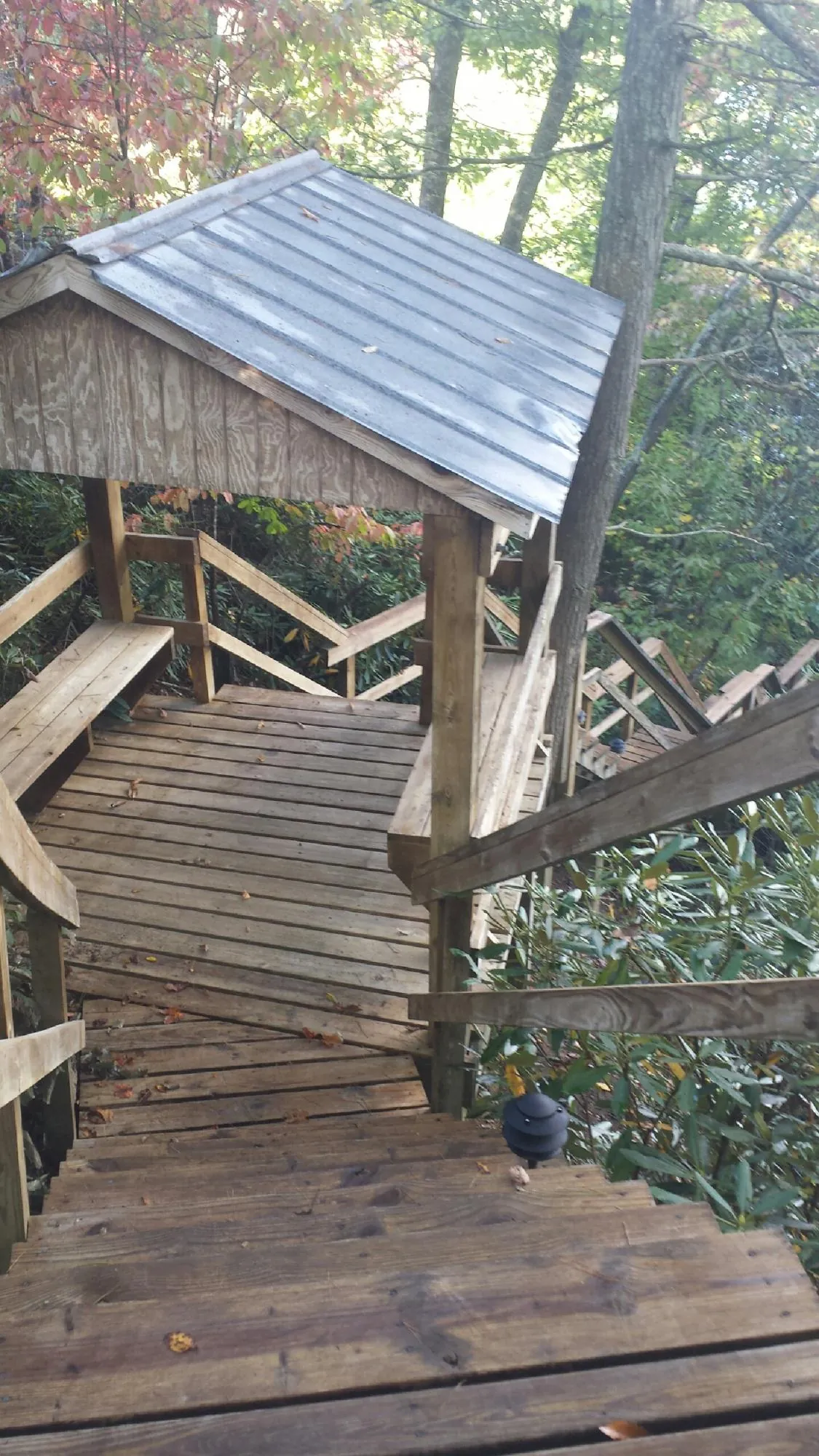 Metal roofed shelter over wooden steps on a wooded walkway — Skylight Repair & Installation work by our crew in Atomic City