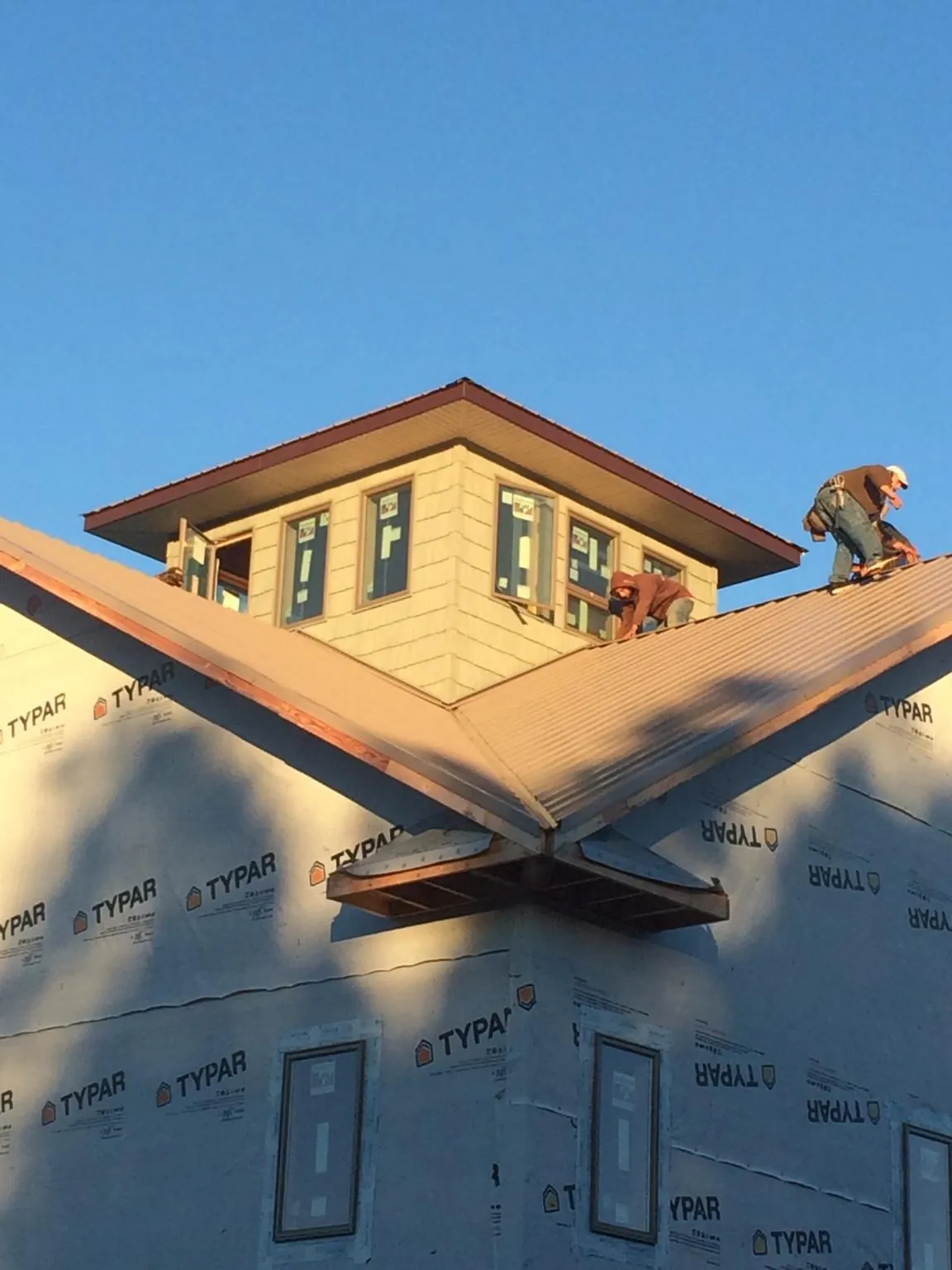 Roofers working around a rooftop cupola on a new metal roof at sunset — Roof Waterproofing in Atomic City by Roofing Brothers